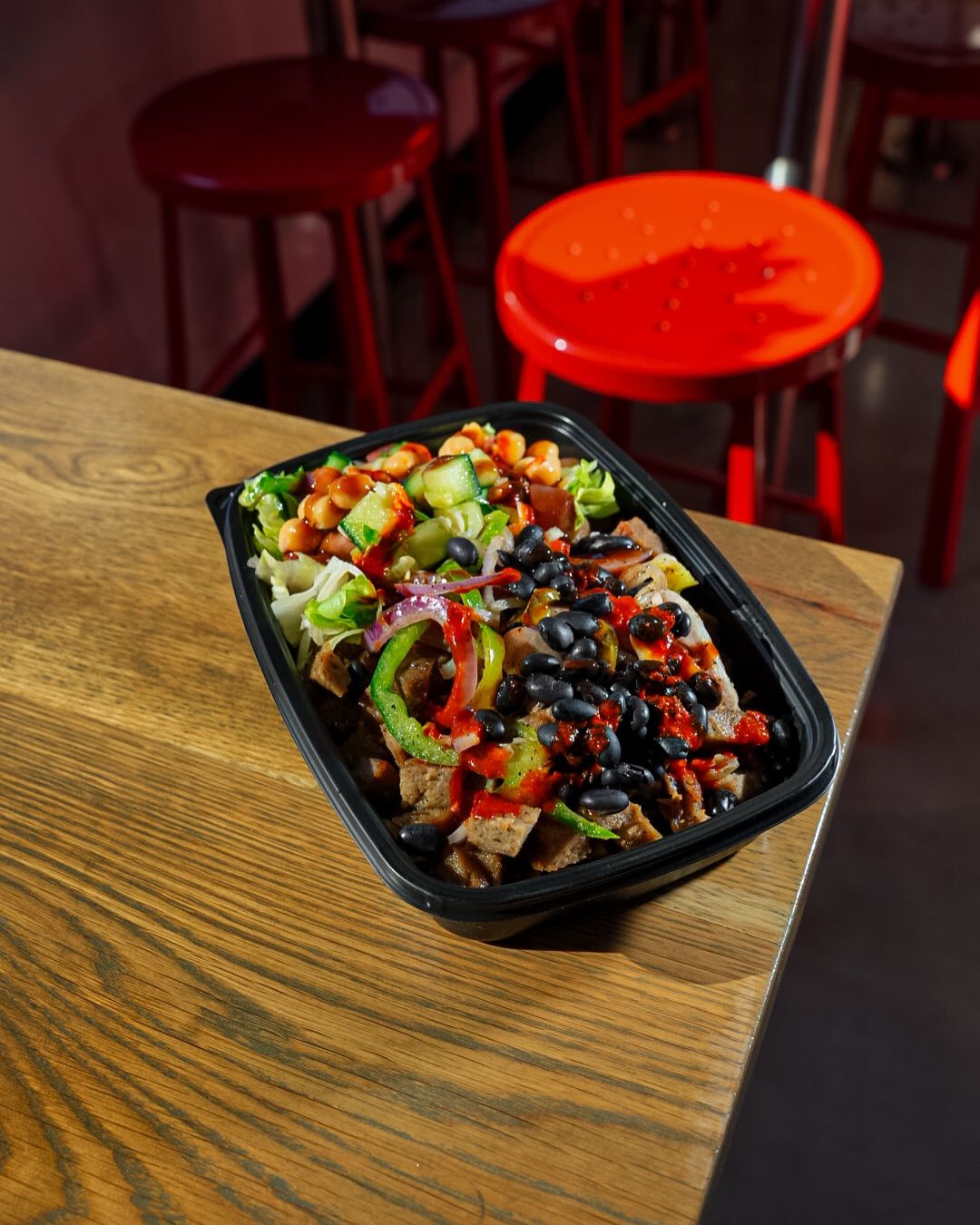 Takeout bowl with gyro meat, black beans and hot sauce